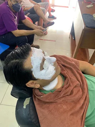 Customer reclined for a straight-razor shave, face lathered with shaving foam